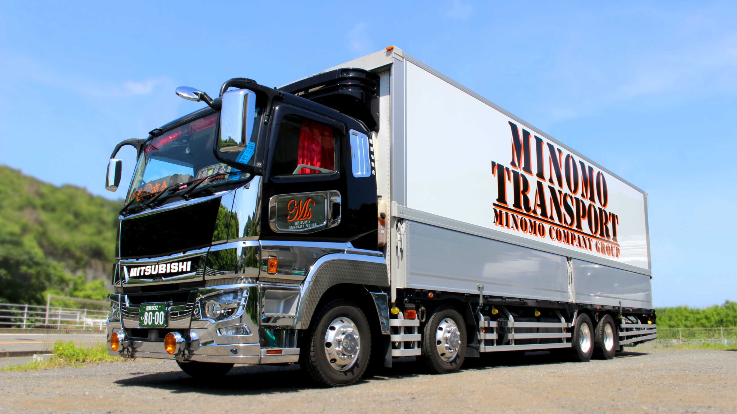 「MINOMOTRANSPORT」と書かれた大型輸送トラックが駐車している様子